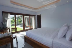 ein Schlafzimmer mit einem weißen Bett und einem Fenster in der Unterkunft Villa Diva in Ketewel