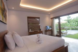 ein Schlafzimmer mit einem weißen Bett mit einem Teddybär darauf in der Unterkunft Villa Diva in Ketewel