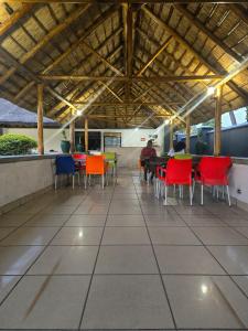 Chicken-Line Restaurant And Take Away في Mponda: فناء مع كراسي ملونة وطاولات في مبنى