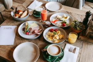 a wooden table topped with plates of food and coffee at QC Quartier Chiemsee Hotel in Seebruck