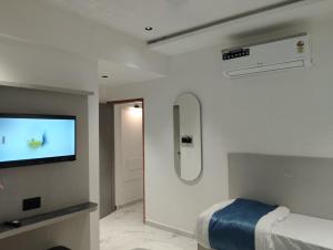 a white room with a bed and a tv at Hotel Palliate Inn in Ahmedabad