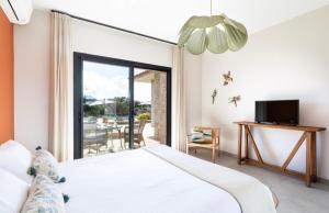 een slaapkamer met een bed en een tv en een balkon bij A Liccia in Pianottoli-Caldarello