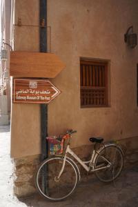 a bike parked next to a building with a sign at Jawharat Alaqar Inn نزل جوهرة العقر in Nizwa