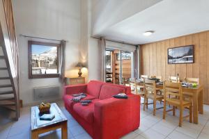 a living room with a red couch and a table at Résidence Goélia L'Aigle Bleu in Briançon