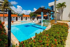 a swimming pool at a resort with palm trees and a building at Sirius Beach Hotel in Natal