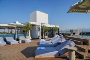 Skylark, Aluma Hotels & Resorts في أثينا: فناء على كراسي زرقاء وطاولات على السطح