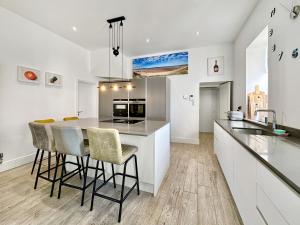 een keuken met witte kasten en een eiland met barkrukken bij Cedars in Mortehoe