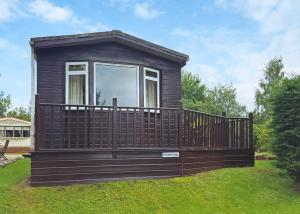 a small cabin with a balcony on the grass at Beech Hedge in Coupar Angus