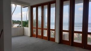 Habitación con puertas y ventanas con vistas al océano. en Pelpatha, en Balapitiya