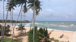 una playa con palmeras y el océano en Pelpatha, en Balapitiya