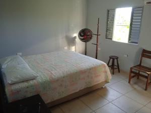 Pousada Refúgio Natural da Ilha في إلها كومبريدا: غرفة نوم بها سرير وكرسي ونافذة