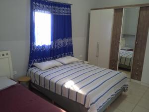 una camera da letto con un letto con tende blu e una finestra di Pousada Refúgio Natural da Ilha a Ilha Comprida