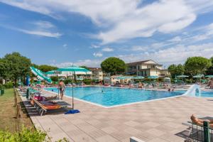 una grande piscina con sedie e ombrelloni di TIGLI Lido Altanea a Caorle