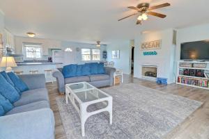 a living room with blue couches and a kitchen at 4140 - Beach Carousel in Kitty Hawk