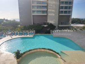 a swimming pool with chairs and a building at Patty del Mar Suites in Santa Marta