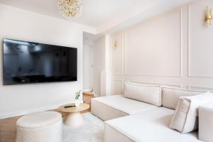 Sublime 3 chambres a Montmartre avec Clim et Jacuzzi في باريس: غرفة معيشة بيضاء مع أريكة بيضاء وتلفزيون