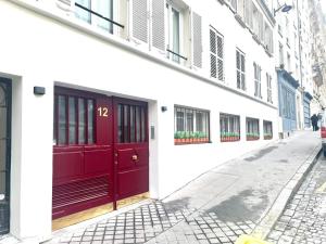 Sublime 3 chambres a Montmartre avec Clim et Jacuzzi في باريس: باب احمر على مبنى ابيض على شارع