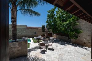 a patio with a table and chairs and a palm tree at Villa To Palati with Private Pool Anogyra in Anoyira