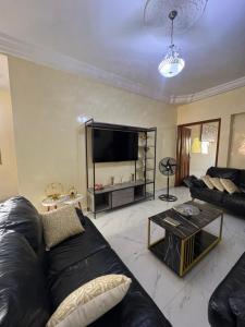 a living room with a black couch and a tv at Express at home in Dakar