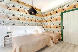 zwei Betten in einem Schlafzimmer mit einer bienenbedeckten Wand in der Unterkunft Executive Hotel Evolution - Spiaggia Inclusa in Cesenatico