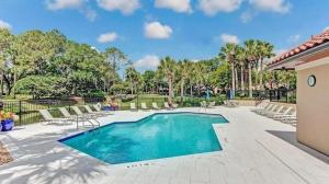 a swimming pool in a courtyard with chairs and trees at Sandy Dunes - Cozy 3BR w beach, pool & sunroom in Ponte Vedra Beach
