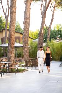 Ein Mann und eine Frau gehen einen Bürgersteig entlang. in der Unterkunft Executive Hotel Evolution - Spiaggia Inclusa in Cesenatico