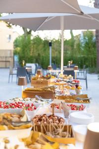 ein Buffet mit Speisen auf einem Tisch unter einem Sonnenschirm in der Unterkunft Executive Hotel Evolution - Spiaggia Inclusa in Cesenatico