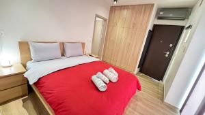 a bedroom with a red bed with two white towels on it at Karanasiou Apartment in Tríkala