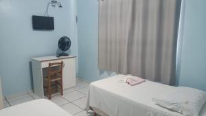 Habitación pequeña con 2 camas y TV. en Hotel BR, en Videira