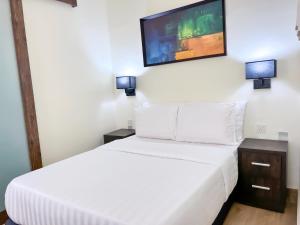 Un dormitorio con una cama blanca y un televisor de pantalla plana. en Serene Heights Hotel, en Maiyegun