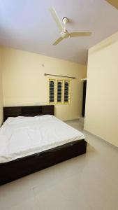 une chambre avec un lit avec un ventilateur de plafond dans l'établissement Maruthi Comforts, à Bangalore