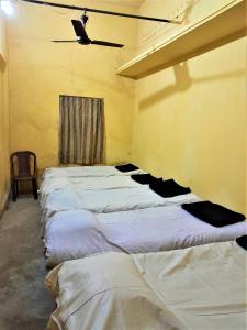 a room with five beds lined up against a wall at The OLD house in Bolpur