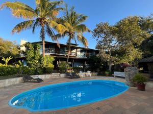 a swimming pool in front of a house with palm trees at Pousada Recanto da Serra in Serra do Cipo