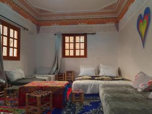 a room with two beds and a couch and windows at Dar Imoughlad in Marrakesh