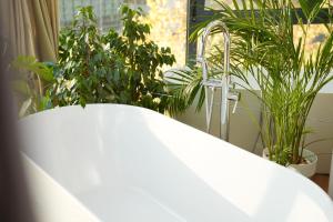 a white bath tub next to a window with plants at Moonlight Apartments Tirana in Tirana