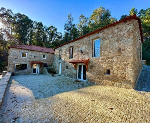 Una antigua casa de piedra con un camino de entrada delante de ella. en Casas da Casa do Telhô, en Celorico de Basto