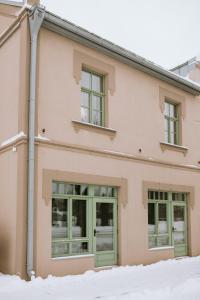 Renovated City Centre Apartment في مادونا: مبنى وردي اللون بأبواب خضراء وسط الثلج