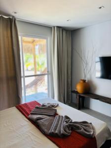 a hotel room with a bed with towels on it at Jaguarype Bangalôs in Fortim