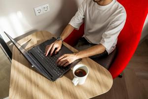 Holiday Inn Express Porto - Boavista by IHG في بورتو: رجل يجلس على طاولة مع جهاز كمبيوتر محمول