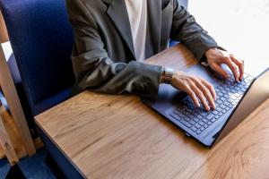 Holiday Inn Express Porto - Boavista by IHG في بورتو: رجل يرتدي بدلة يكتب على جهاز كمبيوتر محمول