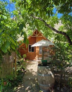 a log cabin with an umbrella and a barrel at Carolin Cacao - Cabaña Nogal in San José de Maipo