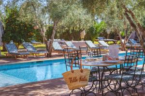 a table and chairs next to a swimming pool at Boutique Hotel Katia in El Harkat