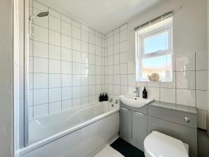 ein weißes Badezimmer mit Badewanne und Waschbecken in der Unterkunft 15 Mins to Sizewell C - Driveway Parking - Contractor Friendly - 2 Bedroom in Saxmundham