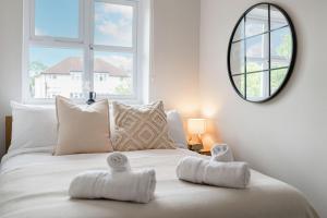 Schlafzimmer mit einem weißen Bett und einem Spiegel an der Wand in der Unterkunft 15 Mins to Sizewell C - Driveway Parking - Contractor Friendly - 2 Bedroom in Saxmundham