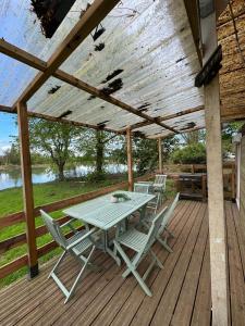 Una terraza de madera con una mesa y sillas. en Chalet de pêche Le Caribou, en Rozay-en-Brie