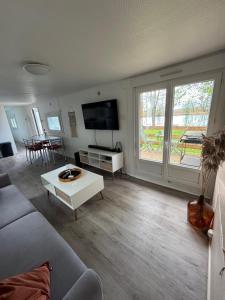 Una sala de estar con un sofá y un televisor. en Chalet de pêche Le Caribou, en Rozay-en-Brie