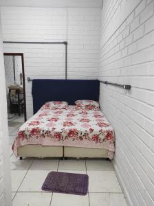 Un dormitorio con una cama en una pared de ladrillo blanco. en Apartamento com churrasqueira 400 metros da praia, en Florianópolis