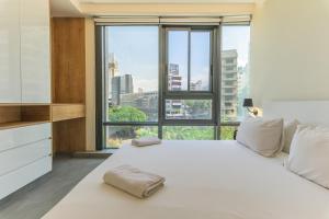 una camera da letto con un grande letto bianco con una grande finestra di Germac Suites a Al Kaslīk