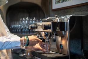a person is making a drink in a espresso machine at Les Monts Charvin in Courchevel