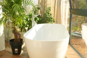 a white bath tub sitting next to potted plants at Moonlight Apartments Tirana in Tirana